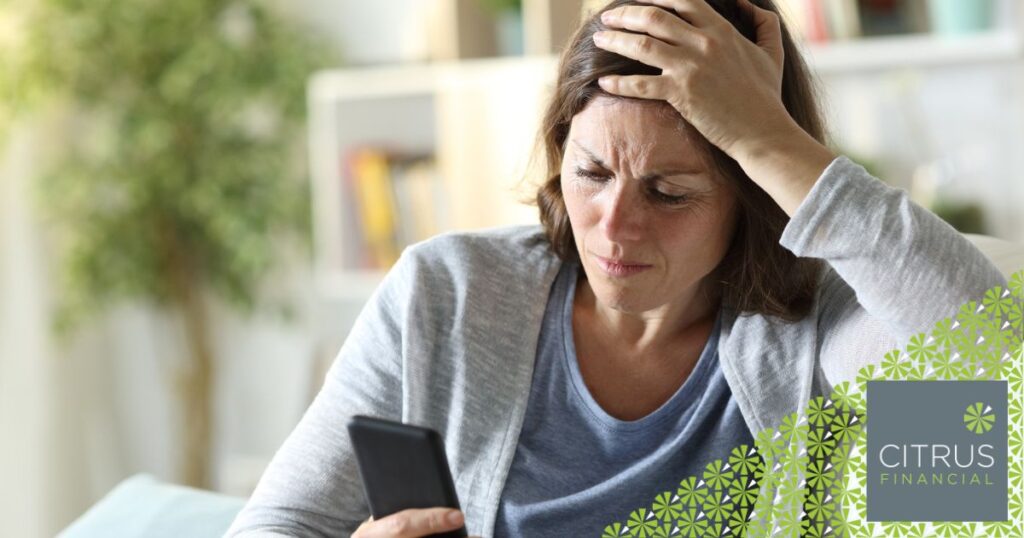 woman sitting on a sofa looking concerned while using her mobile phone
