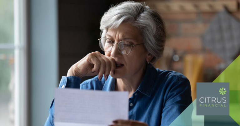 Silver-haired older woman looking worried as she reads a sheet of paper